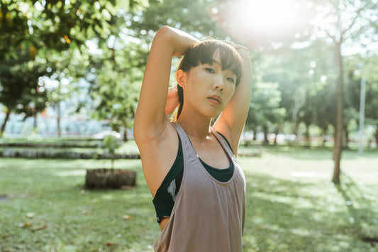 Woman stretching outdoors in sunlight, embodying natural energy and vitality
