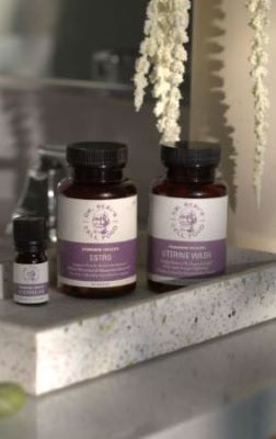 Dr. Sebi herbal supplement bottles displayed on marble countertop with decorative dried flowers overhead.